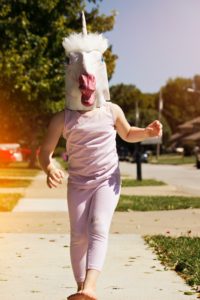 Girl skipping while wearing unicorn mask